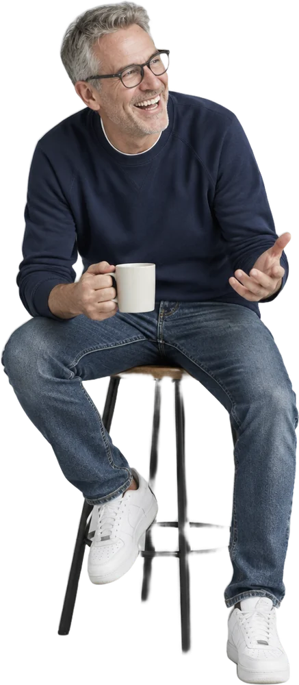 A man laughing on a stool with a coffee